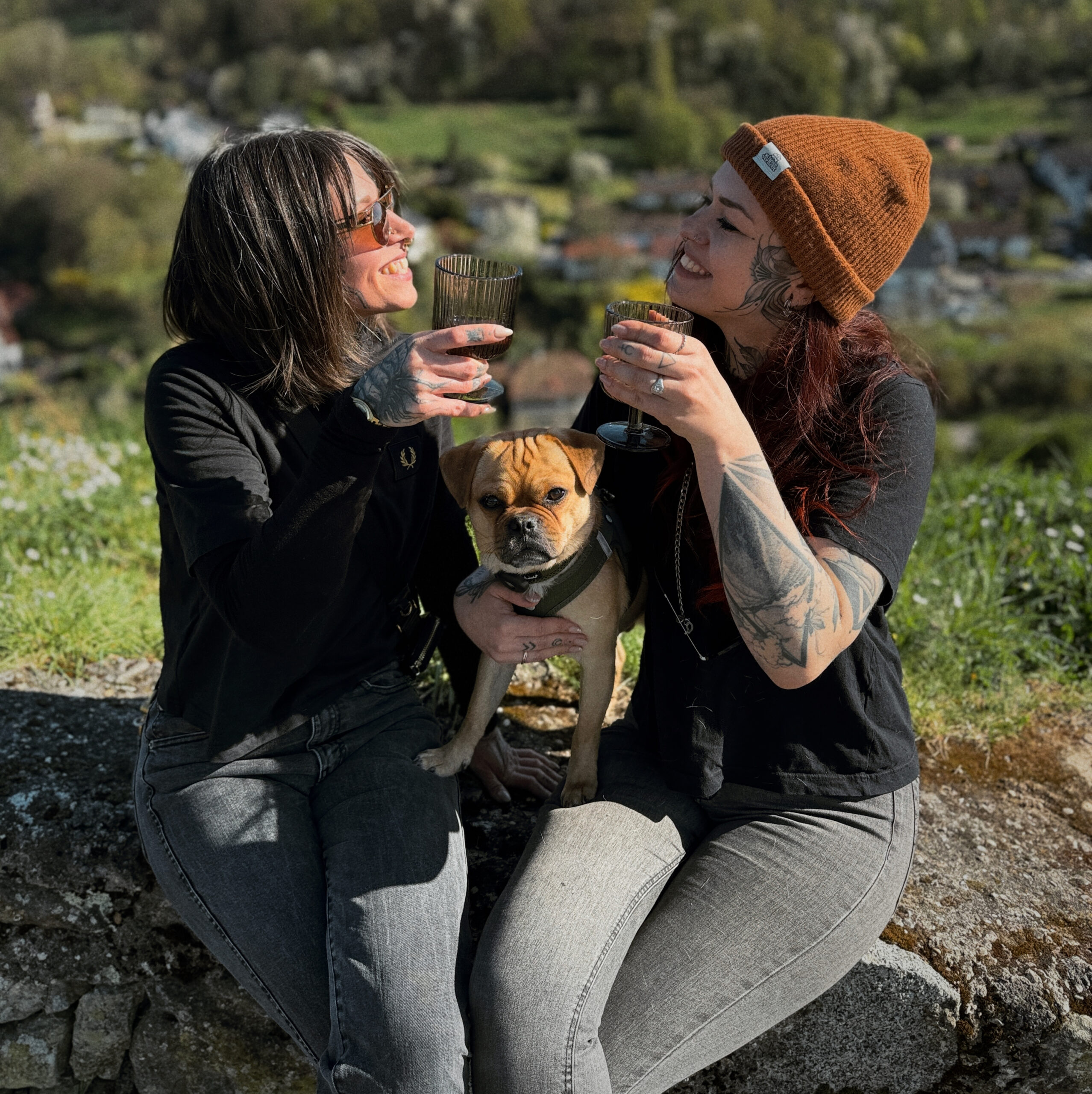 Karo und Charmaine prosten zusammen an, Hund Pepe sitzt zwischen ihnen