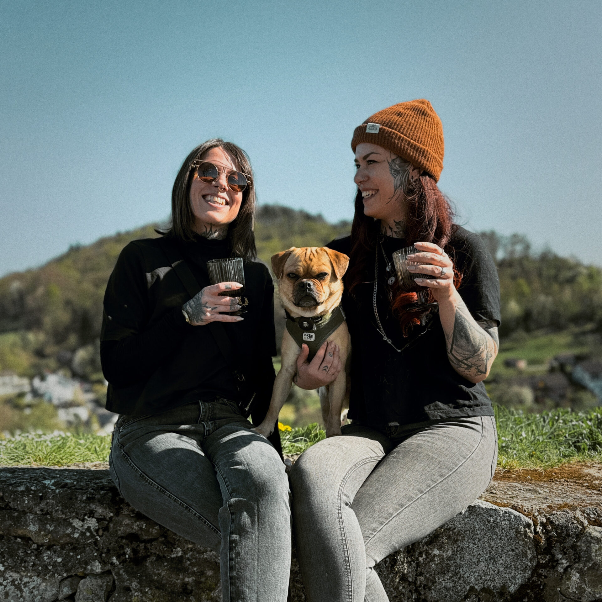 Karo und Charmainesitzehn mit Hund Pepe auf der Mauer